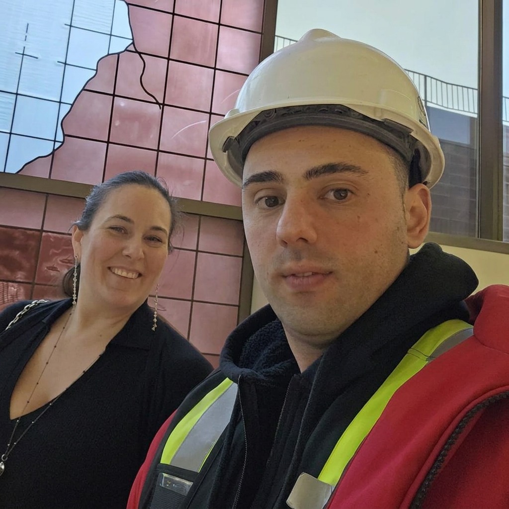The founders of Luminova Construction on site, one wearing a hard hat and high-visibility vest